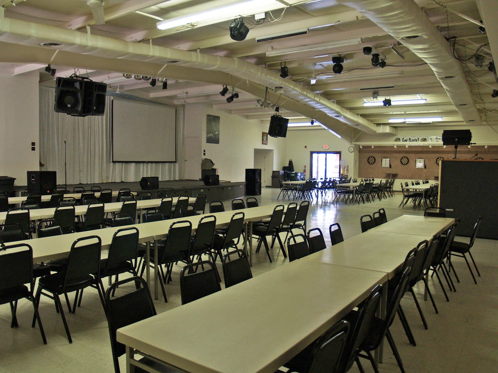 Large social hall with stage, sound system, and rows of tables and chairs