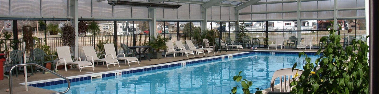 Indoor pool with lounge chairs and plants in a climate-controlled enclosure