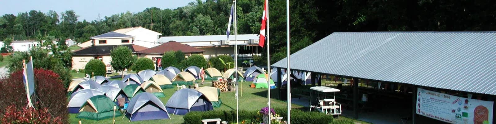 Colorful tents set up in shaded campsite with flags flying at White Tail Resort